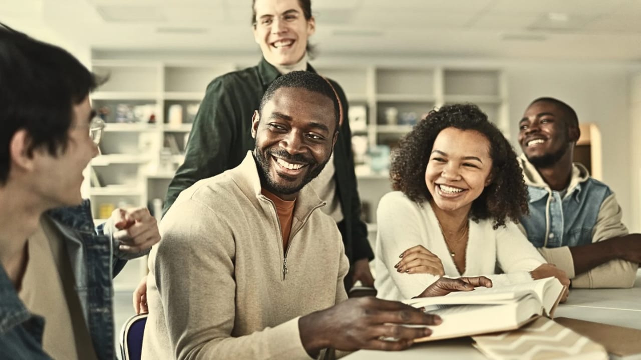Students laughing together around a table during a club session