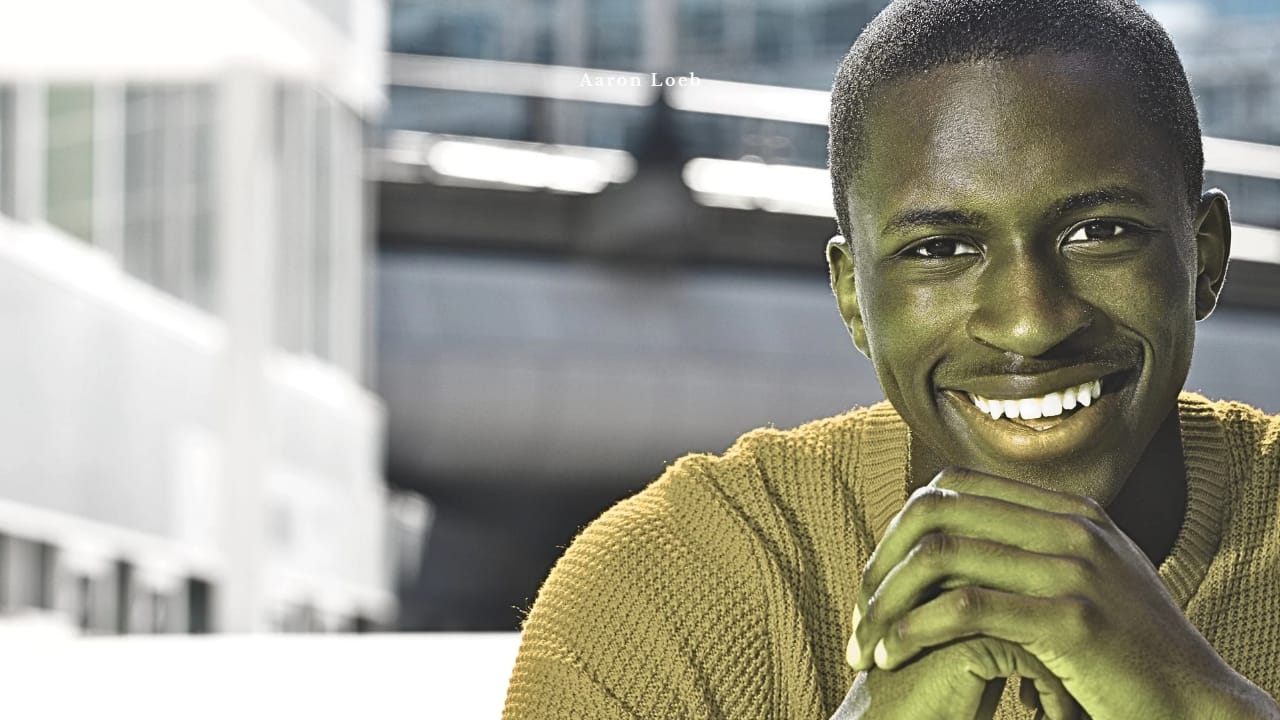 A young man resting his chin on his hands, smiling