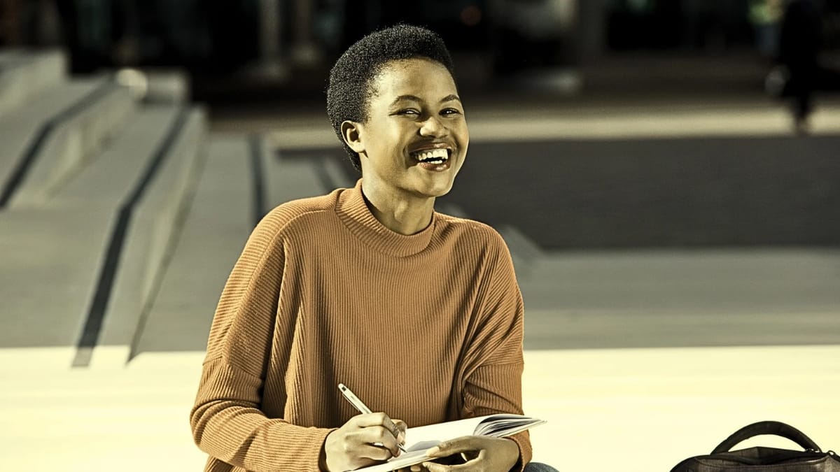 A student writing in a notebook outside her campus